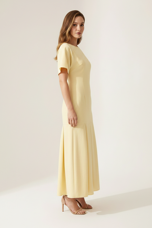 A woman modeling a pale yellow midi dress with short flutter sleeves, a boat neckline, and a flared skirt, photographed against a plain light beige studio background.