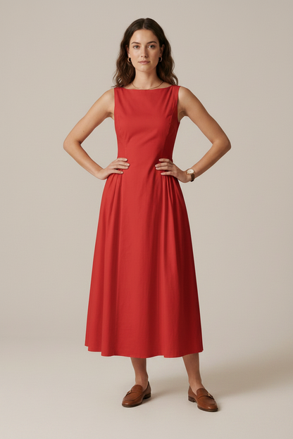 A woman modeling a sleeveless red midi dress with a boat neckline and gathered waist, paired with brown loafers, against a plain beige studio background.