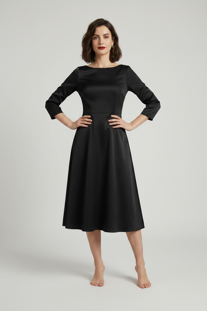 A woman modeling a black three-quarter sleeve fit-and-flare midi dress with a boat neckline, holding a black clutch purse against a light gray studio background.