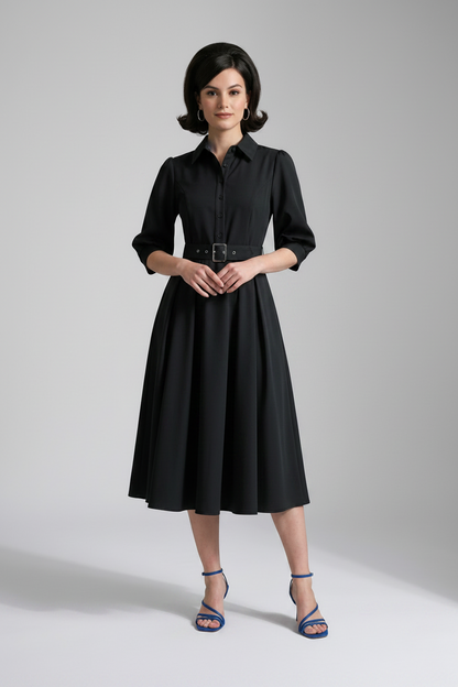 A woman modeling a black midi shirt dress with puff sleeves, a pointed collar, and a matching black belt with a silver buckle, paired with blue strappy heels against a light gray studio background.