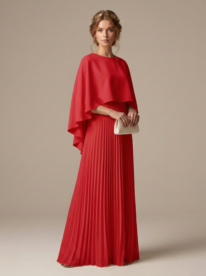 A woman models a vibrant red formal gown featuring a draped cape-style bodice and a pleated maxi skirt, holding a small cream clutch against a solid beige studio background.