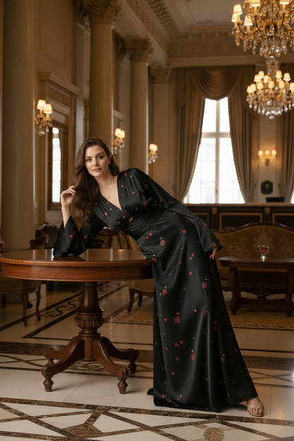 A woman stands in a grand, elegant ballroom wearing a floor-length black satin gown decorated with small red floral motifs. The room features ornate chandeliers, high windows with drapes, and classic furniture.