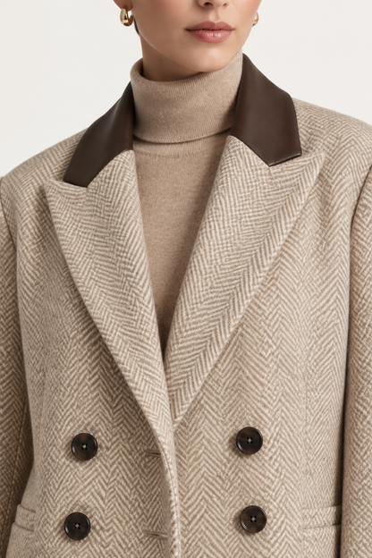 Close-up of a model wearing a beige herringbone double-breasted coat with dark brown lapels and dark brown buttons, layered over a beige turtleneck sweater.