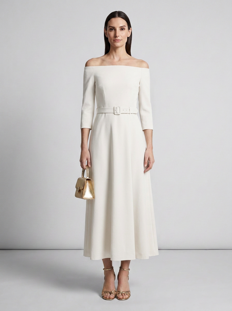 A woman models an off-the-shoulder midi dress in off-white with a matching belt and silver buckle. She is holding a small metallic gold handbag and wearing gold strappy heels, set against a neutral light gray studio background.