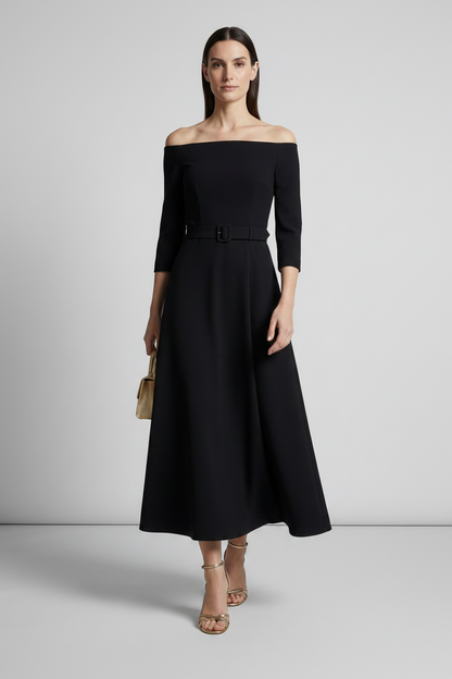 A woman models an off-the-shoulder black midi dress with three-quarter sleeves and a matching black belt at the waist, styled with nude high-heeled sandals and a small beige handbag against a light gray studio background.