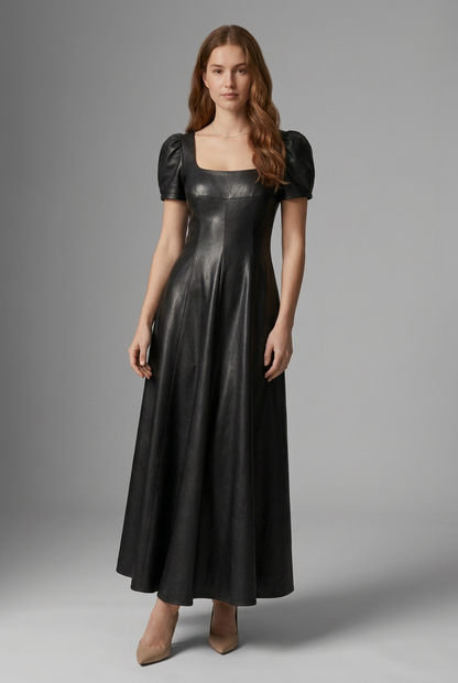A woman modeling a black faux-leather midi dress with puff sleeves, a square neckline, and a flared skirt, photographed against a neutral gray studio background.