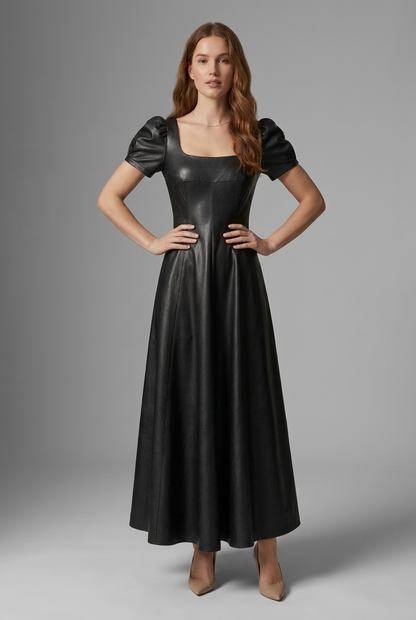A woman modeling a black faux-leather midi dress with puff sleeves, a square neckline, and a flared skirt, photographed against a neutral gray studio background.