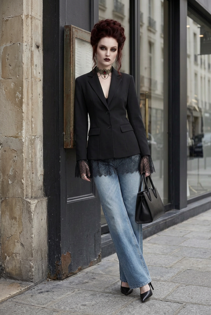 A model stands on a city sidewalk wearing a black blazer, wide-leg light blue jeans, black lace-trimmed gloves, a black choker, and black heels, holding a black handbag.