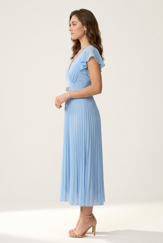 A woman modeling a light blue pleated midi dress with ruffled cap sleeves, a deep V-neckline, and a decorative silver bow detail at the waist, set against a plain off-white studio background.