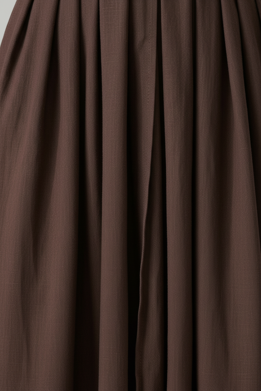 A woman modeling a dark brown midi wrap dress with short flutter sleeves, a deep V-neckline, and a drawstring waist, paired with brown strappy sandals against a neutral studio background.