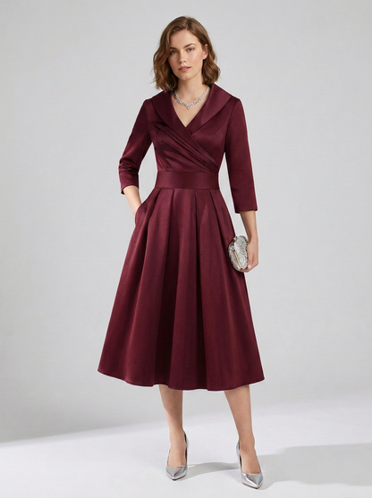 A woman models a three-quarter sleeve wrap-style midi dress in deep burgundy. The dress features a structured collar, a defined waistband, and a flared skirt.