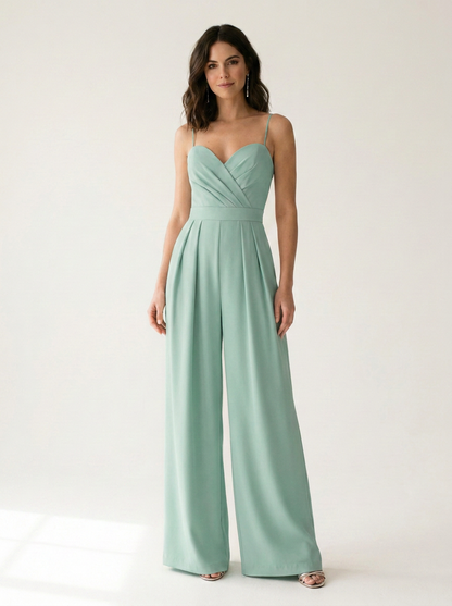A woman modeling a sage green wide-leg jumpsuit with spaghetti straps and a sweetheart neckline, standing against a plain white studio background.